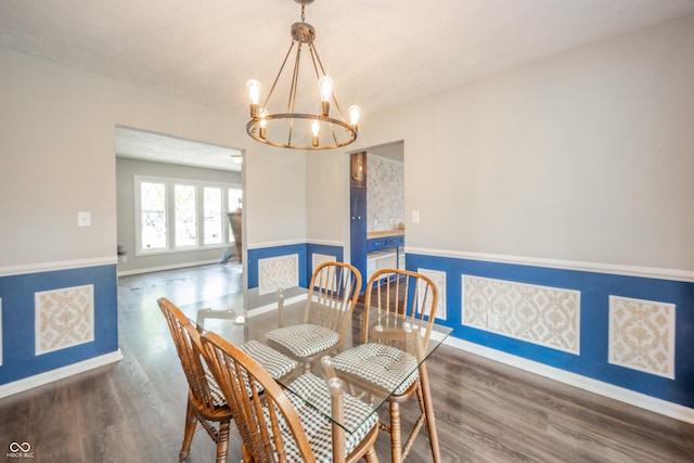 dining space featuring baseboards, a notable chandelier, wainscoting, and wood finished floors