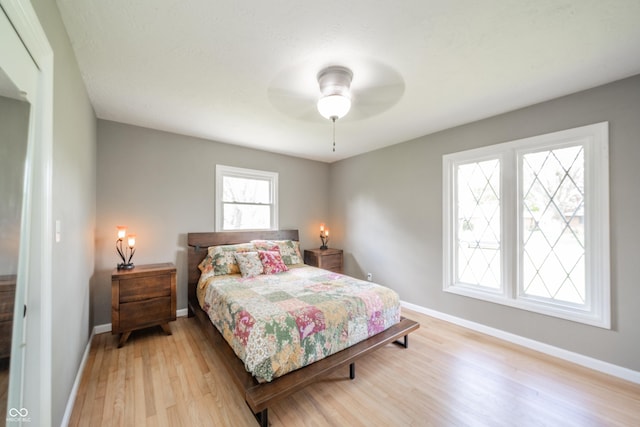 bedroom featuring baseboards, ceiling fan, and light wood-style flooring