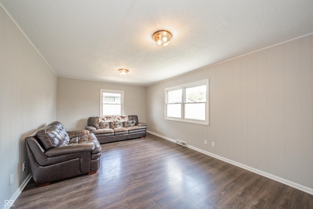 living area with dark wood-style flooring, baseboards, and visible vents