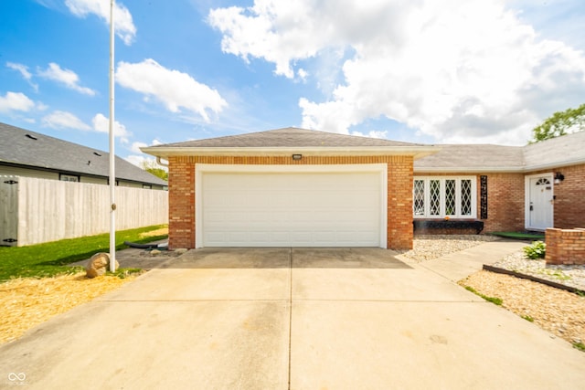 view of front of home featuring brick siding, an attached garage, driveway, and fence