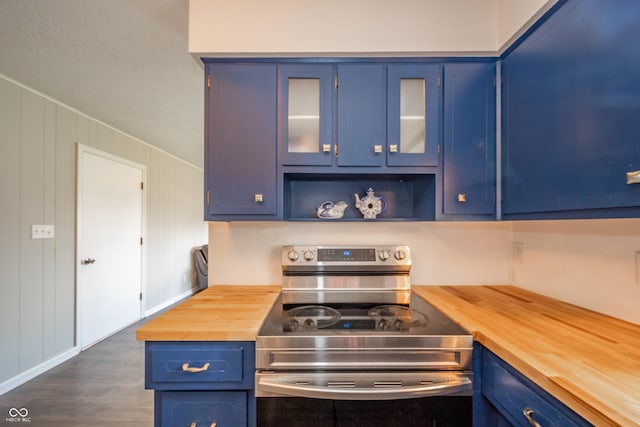 kitchen with glass insert cabinets, butcher block countertops, dark wood-type flooring, stainless steel range with electric cooktop, and blue cabinetry