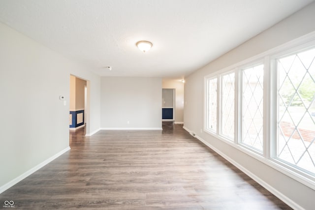 unfurnished living room featuring baseboards, plenty of natural light, and wood finished floors
