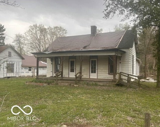 view of front of house featuring a porch, a front lawn, and a chimney