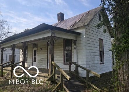 view of home's exterior featuring covered porch and a chimney