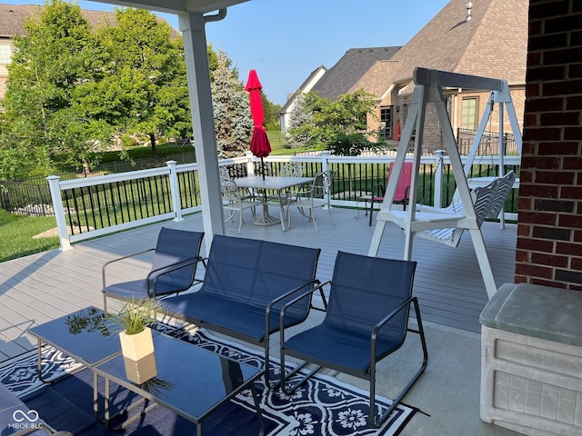 view of patio with a deck, fence, and outdoor dining space