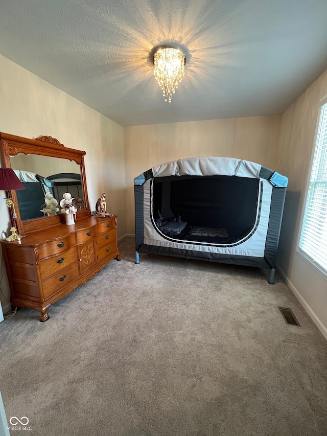carpeted bedroom featuring a notable chandelier, baseboards, and visible vents