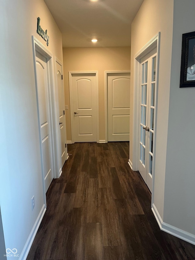 hall with dark wood-style flooring, baseboards, and french doors