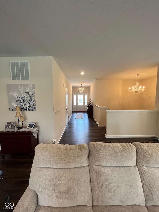 living room featuring baseboards, a notable chandelier, visible vents, and dark wood finished floors