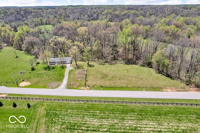 drone / aerial view featuring a view of trees and a rural view