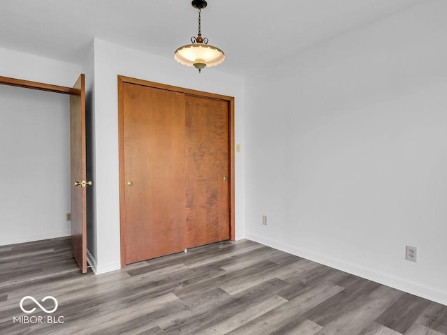 unfurnished bedroom with a closet, baseboards, and wood finished floors