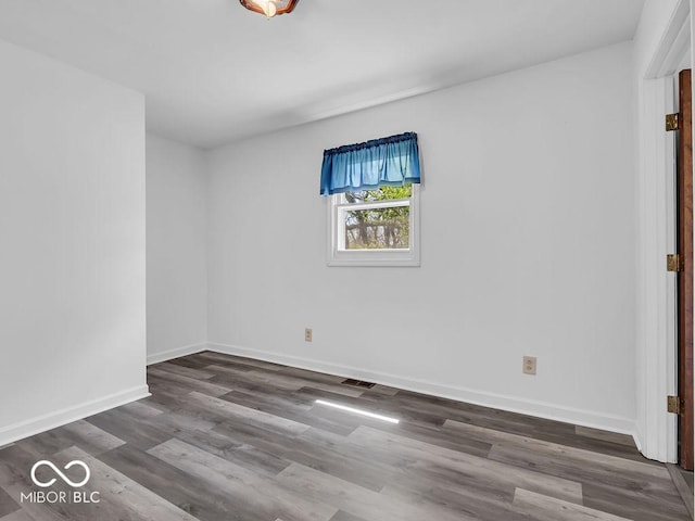 unfurnished room with baseboards, wood finished floors, and visible vents