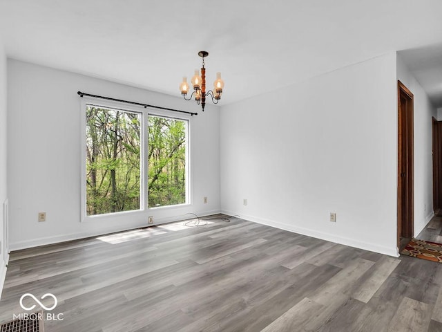unfurnished dining area featuring an inviting chandelier, baseboards, and wood finished floors