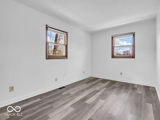 empty room with visible vents, baseboards, and wood finished floors