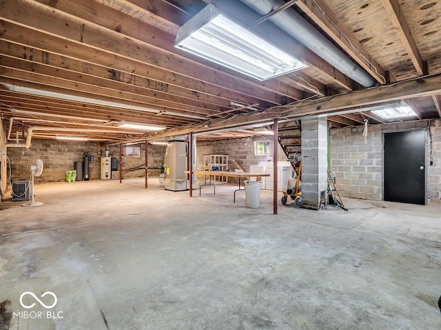 unfinished basement with heating unit, fridge, and electric water heater