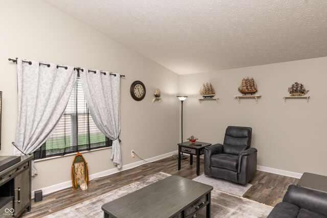 living area featuring baseboards, a textured ceiling, and wood finished floors