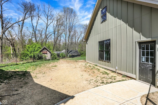 view of side of property with a patio, board and batten siding, and fence