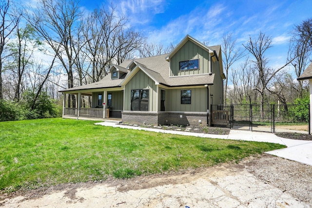 back of house with a porch, a gate, board and batten siding, and a lawn