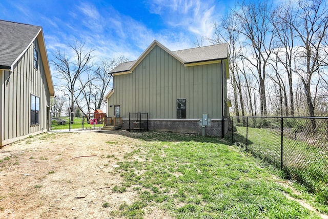 exterior space with board and batten siding, roof with shingles, a lawn, central AC unit, and a fenced backyard