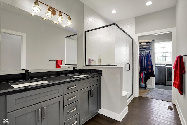 bathroom with visible vents, a sink, a shower stall, and washing machine and clothes dryer