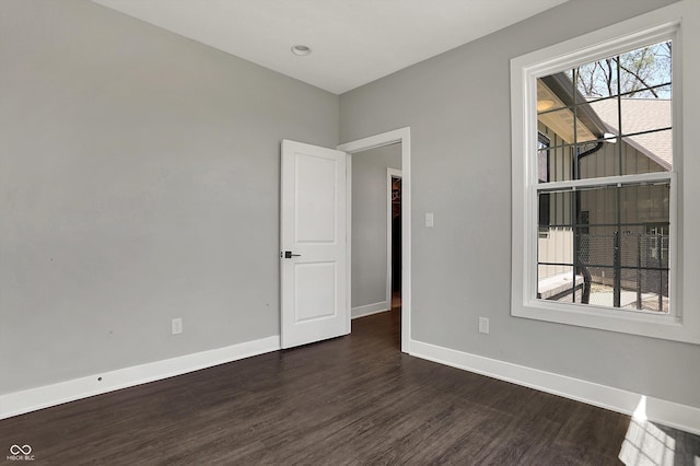 empty room with baseboards and dark wood-style flooring
