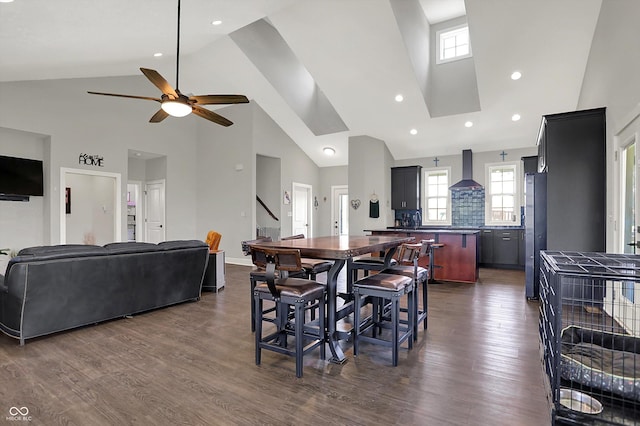 dining room with a ceiling fan, dark wood finished floors, stairs, and high vaulted ceiling