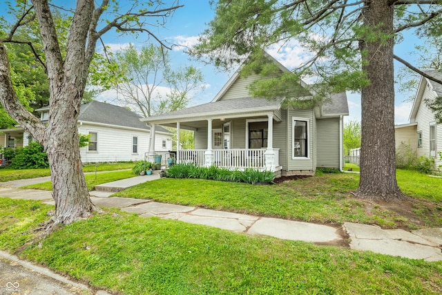 view of front facade with covered porch, a shingled roof, and a front yard