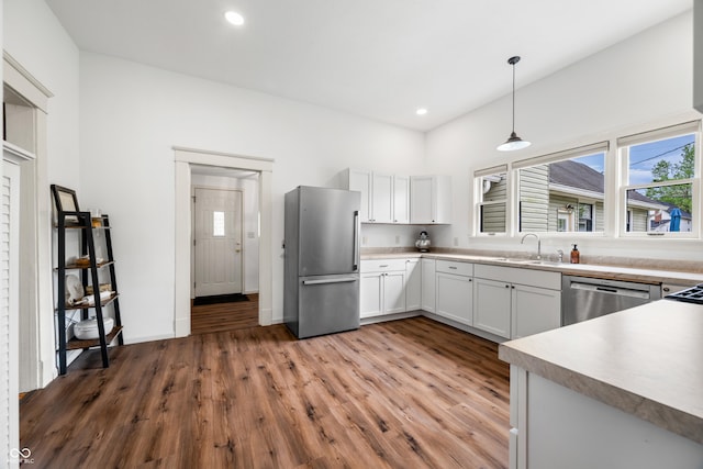 kitchen with stainless steel appliances, a healthy amount of sunlight, a sink, and light wood-style floors