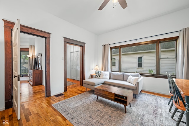 living area featuring ceiling fan, visible vents, baseboards, and light wood-style floors