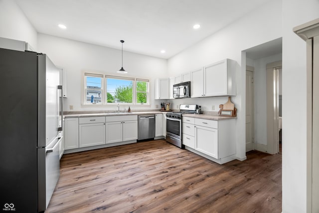 kitchen featuring white cabinets, a sink, light countertops, stainless steel appliances, and wood finished floors