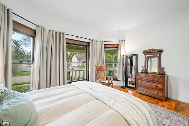 bedroom featuring access to exterior, wood finished floors, and multiple windows
