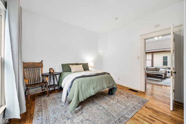 bedroom featuring baseboards, visible vents, and wood finished floors