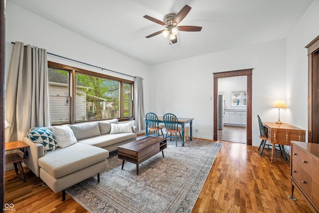 living room featuring ceiling fan, baseboards, and light wood-type flooring