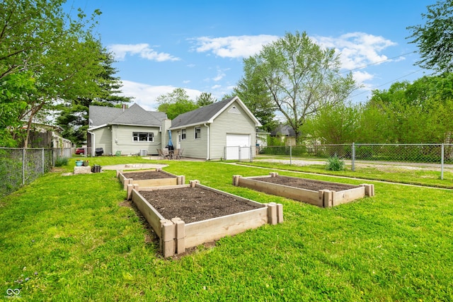 view of yard featuring a fenced backyard, a detached garage, and a garden