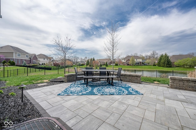 view of patio / terrace featuring a water view, a fenced backyard, outdoor dining area, and a residential view