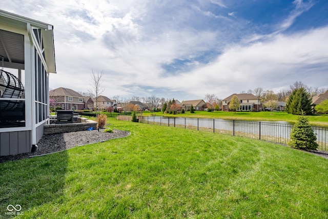 view of yard featuring a water view, fence, and a residential view