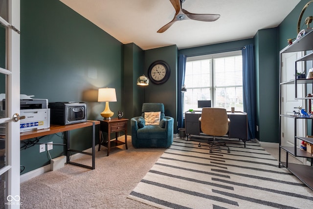 carpeted office space with a ceiling fan and baseboards