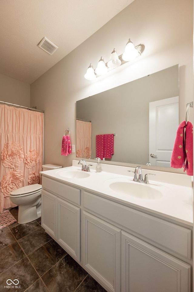 bathroom featuring visible vents, a sink, double vanity, and toilet