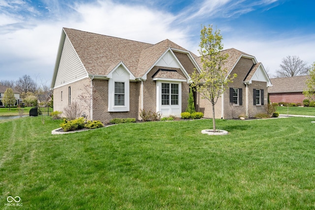 view of front of home with brick siding, roof with shingles, and a front lawn