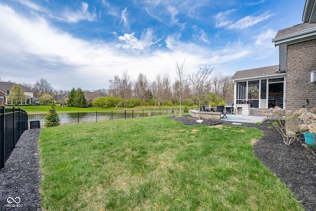 view of yard with fence, a water view, a sunroom, and a patio area