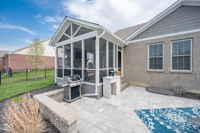 view of patio featuring area for grilling, fence, and a sunroom