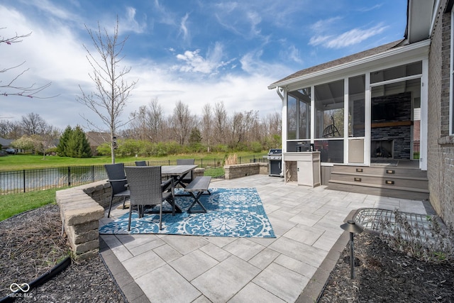 view of patio / terrace featuring area for grilling, a sunroom, fence, a water view, and outdoor dining space