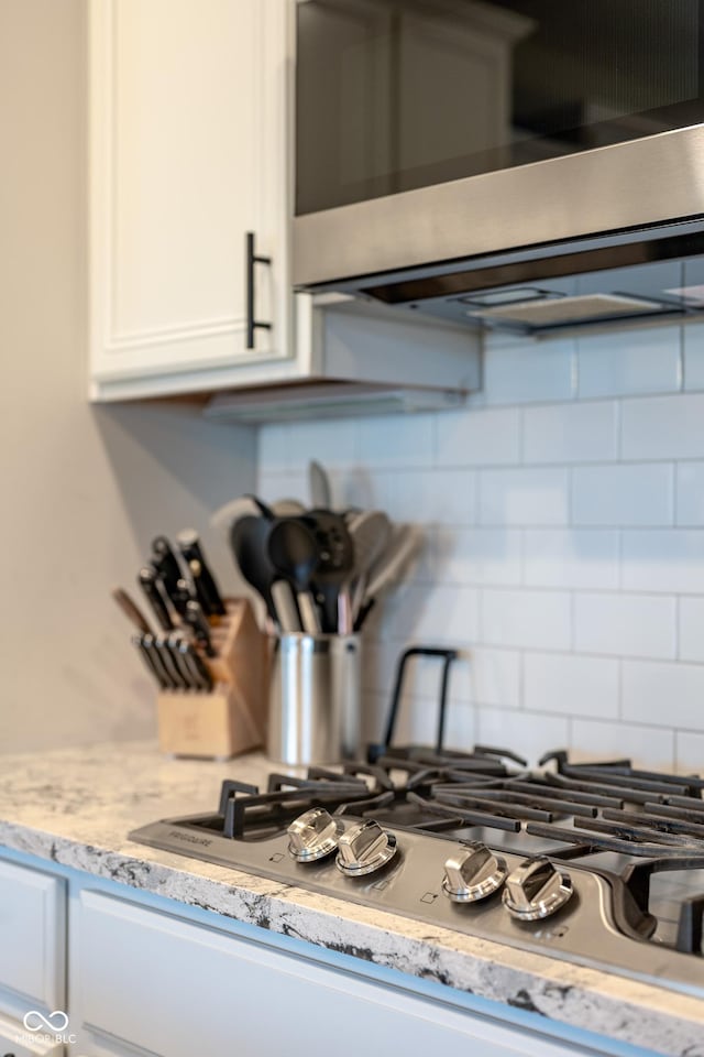 room details with tasteful backsplash, white cabinets, light stone countertops, and stainless steel appliances
