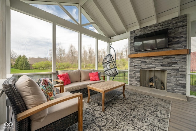 sunroom / solarium with a healthy amount of sunlight, beamed ceiling, and an outdoor living space with a fireplace