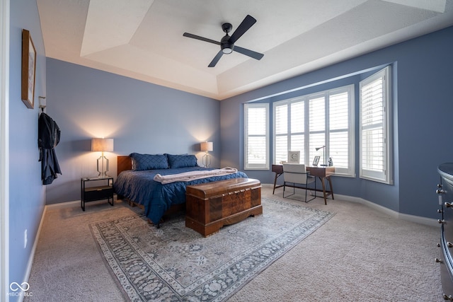 carpeted bedroom featuring baseboards, a ceiling fan, and a raised ceiling