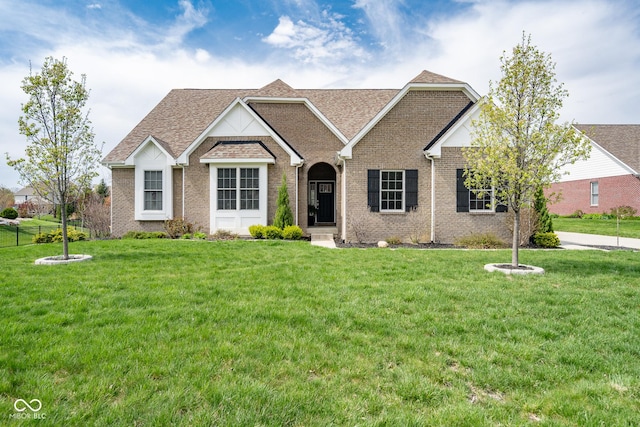 ranch-style home with a shingled roof, a front lawn, and brick siding
