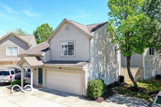 view of front facade with a garage, fence, central AC unit, a shingled roof, and concrete driveway