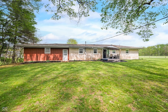 rear view of house featuring fence, stone siding, board and batten siding, a lawn, and a patio