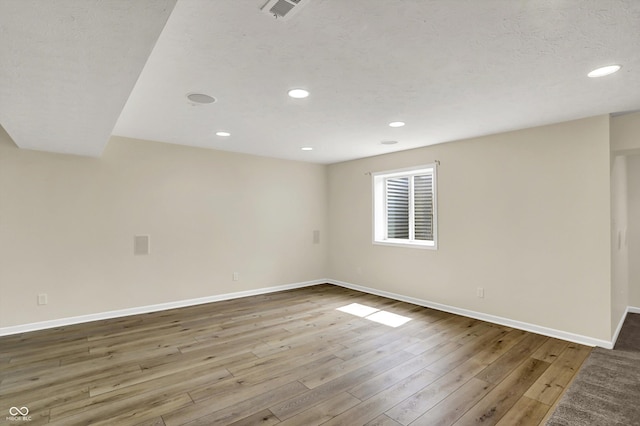 spare room featuring baseboards, wood finished floors, and recessed lighting