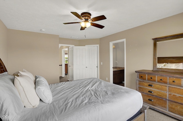 carpeted bedroom with ensuite bath and ceiling fan