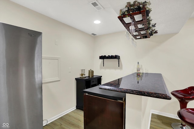 bar area featuring freestanding refrigerator, light wood-style flooring, baseboards, and recessed lighting